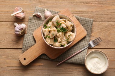 Bir kase lezzetli maydanozlu haşlanmış hamur köftesi ve ahşap arka planda ekşi krema.