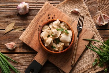 Tahta arka planda maydanozlu ve sarımsaklı bir kase lezzetli haşlanmış hamur köftesi.