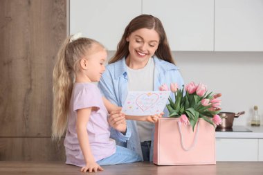 Anneler Günü 'nde annesini laleler ve kartpostalla selamlayan tatlı küçük bir kız.