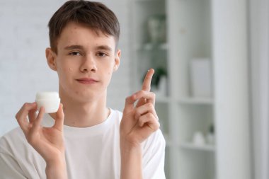 Sivilceli genç çocuk banyoda krem sürüyor, yakın plan.