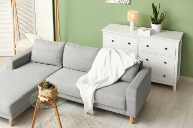 Oturma odasında çekmeceleri ve cam masası olan gri kanepe.