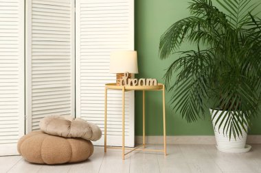 Masa, lamba, puf, tropikal avuç içi ve katlanabilir ekranlı modern odanın içi