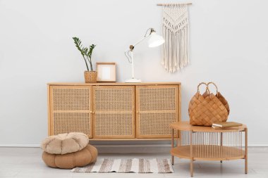 Hasır çantalı bir masa ve odasındaki parlak lambalı ahşap çekmeceler.