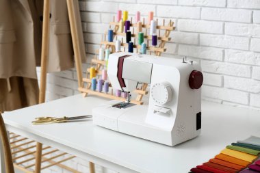 Atölyede terzi masasında dikiş makinesi, yakın plan.