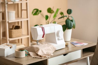 Atölyedeki terzi masasına kumaş ve bitki dikme makinesi.