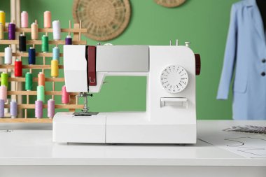 Atölyede terzi masasında dikiş makinesi, yakın plan.