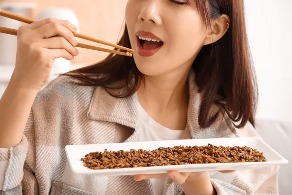 Genç Asyalı kadın evde kızarmış böcek yiyor, yakın plan.