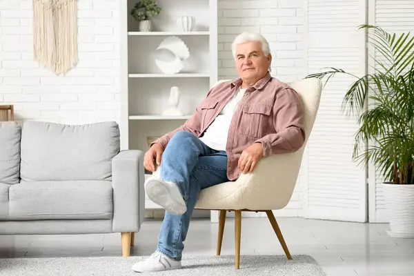 Evdeki koltukta oturan yakışıklı kıdemli adam.