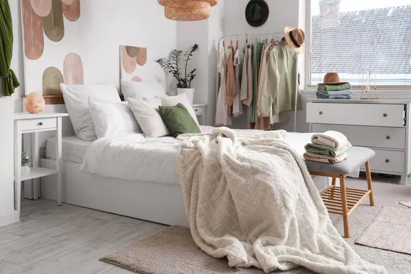 Rahat bir yatak, çekmeceler ve yatak odasının içinde şık kıyafetler.