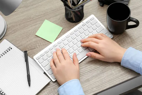 Ofisteki masada bilgisayar klavyesinde yazan kadın, üst görünüm