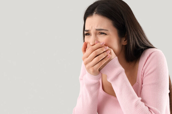 Молодая женщина плохо себя чувствует на светлом фоне, крупным планом