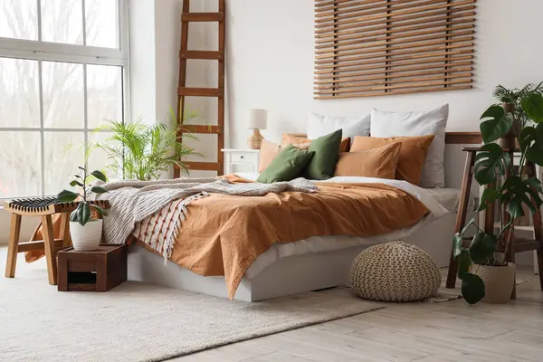 Büyük yataklı, masalı ve bitkilerli rahat bir yatak odası.