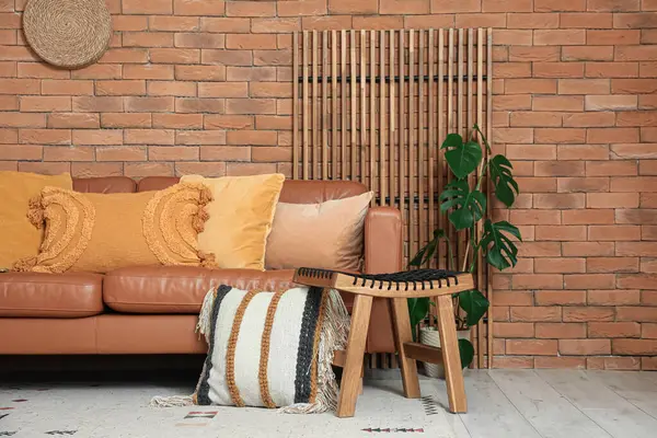 Rahat bir kanepe, minderli bir tabure ve oturma odasının iç tarafında bitkiler.