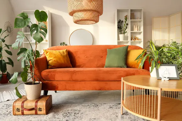 Kahverengi kanepesi, çiçekleri, sehpası ve aynası olan şık bir oturma odası.