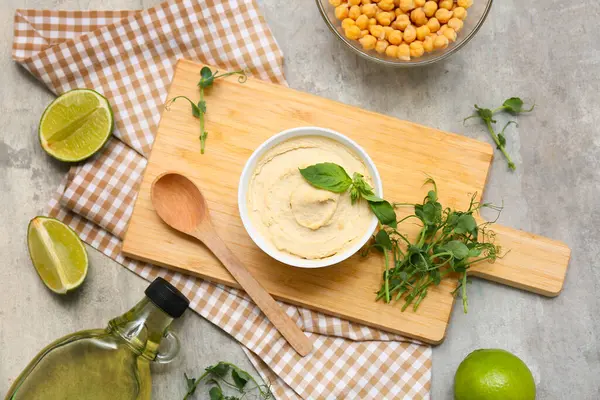 Bir kase lezzetli humus, içinde malzemeler, peçete ve ahşap tahta ve gri grunge arka plan.