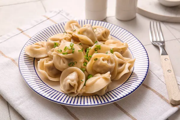 Beyaz fayanslı yeşil soğanlı kaynamış hamur köftesi tabağı, yakın plan.