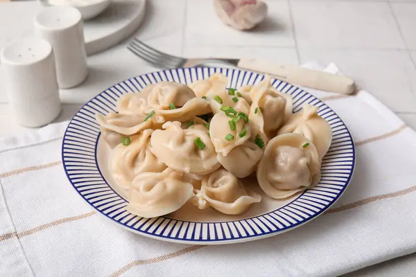 Beyaz fayanslı yeşil soğanlı kaynamış hamur köftesi tabağı, yakın plan.