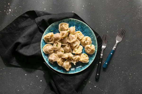 Siyah arkaplanda yeşil soğanlı lezzetli haşlanmış hamur köfteleri.