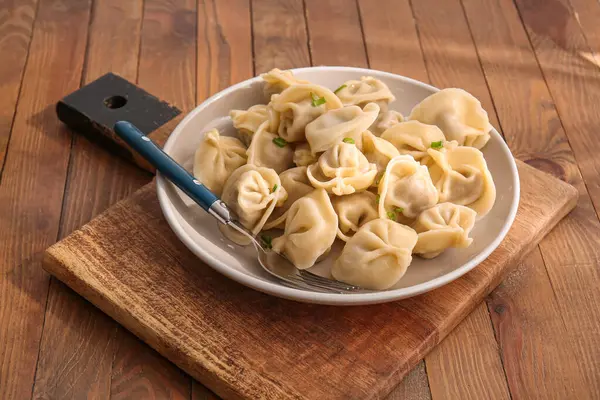 Ahşap arka planda lezzetli kaynamış hamur tatlısı tabağı, yakın plan.