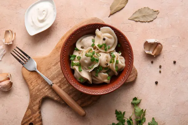 Bir kase lezzetli haşlanmış hamur köftesi, yeşil soğan ve bej arka planda ekşi krema.