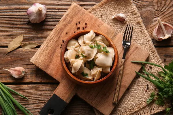 Tahta arka planda maydanozlu ve sarımsaklı bir kase lezzetli haşlanmış hamur köftesi.