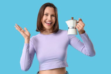 Mavi arka planda gayzer kahve makinesi olan güzel genç bir kadın.