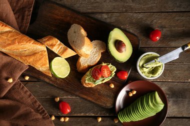 Taze ekmek, lezzetli humus, avokado ve domatesli ahşap zemin.