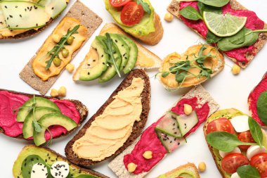 Beyaz arka planda humus, peynir ve sebzeli farklı sandviçler.