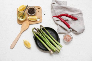 Taze yeşil kuşkonmaz ve beyaz arka planda farklı malzemelerle kızartma tavası.