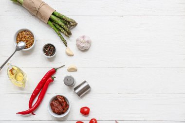 Taze yeşil kuşkonmaz ve beyaz ahşap arka planda farklı malzemeler.