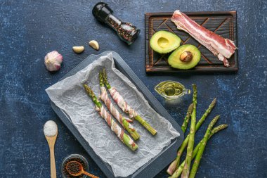 Pastırmalı taze yeşil kuşkonmaz ve mavi arka planda avokado.