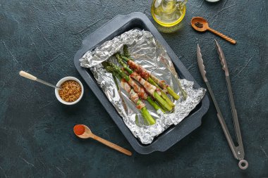 Koyu arkaplanda pastırmalı fırında pişmiş yeşil kuşkonmaz.