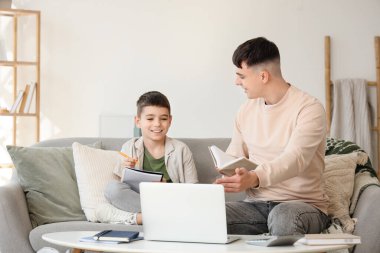 Erkek öğretmeni olan küçük çocuk evde ders çalışıyor.