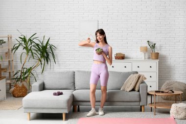 Genç bayan evde taze sebze salatası yiyor.