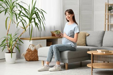 Evde taze sebze salatalı hamile bir kadın var.