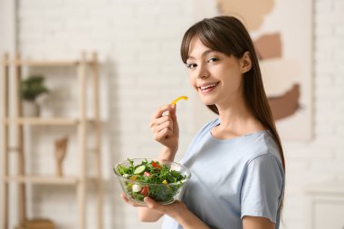 Genç kadın evde taze sebze salatası yemek