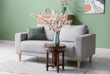 Odanın içinde kanepe ve çiçek açan dallar var.