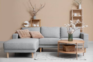 Odanın içi kanepe, raflar ve çiçek açan dallarla dolu.