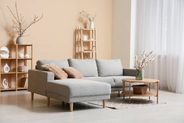 Odanın içi kanepe, raflar ve çiçek açan dallarla dolu.