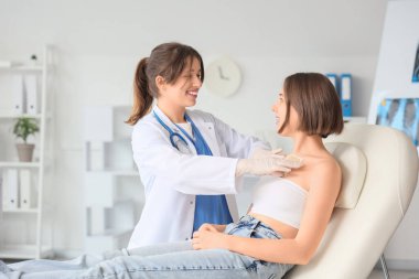 Kadın doktor klinikte hastanın göğsüne hardal yapıştırıyor.