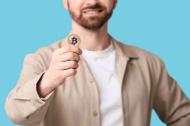 Mavi arka planda bitcoin 'i olan genç adam, yakın plan