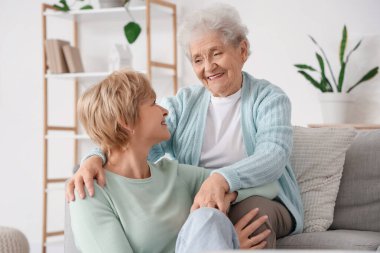 Kıdemli kadın evde kızına sarılıyor. Anneler Günü kutlaması