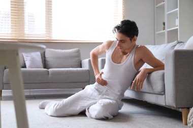 İştahsız genç adam evde yerde oturuyor.