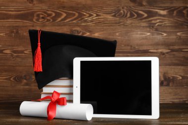 Tahta arka planda kitap, diploma ve modern tablet bilgisayarlı havan topu.