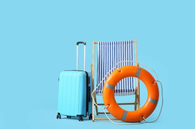 Mavi arka planda can simidi halkası ve bavulu olan çizgili iskemle.