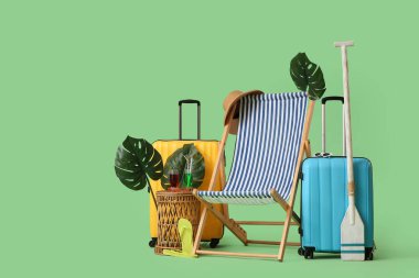 Yeşil arka planda kokteyl, bavul, kürek ve canavar yapraklı çizgili iskemle.