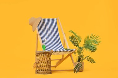 Sarı zemin üzerinde bir bardak kokteyl ve palmiye ağacı olan çizgili iskemle.