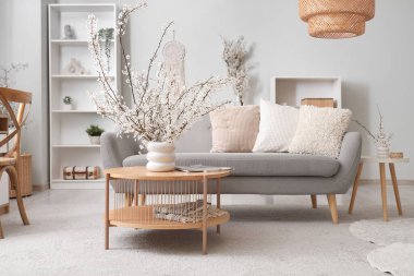 Oturma odasının iç tarafındaki masada çiçek açan dalları ve dergileri olan vazo.