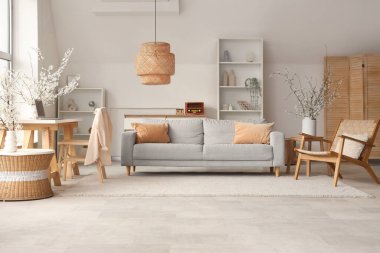 Kanepe, işyeri ve vazolarda çiçek açan dallarla aydınlık oturma odasının içinde.