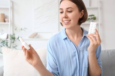 Evinde burun damlası ve hapları olan alerjisi olan genç bir kadın.